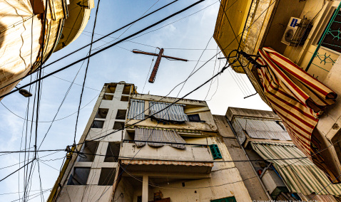 A wooden cross hanging next to the electricity wires in Bourj Hammoud, Beirut