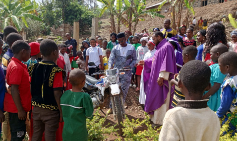 Parishioners and a priest gathered around the new motorbike in Bamenda