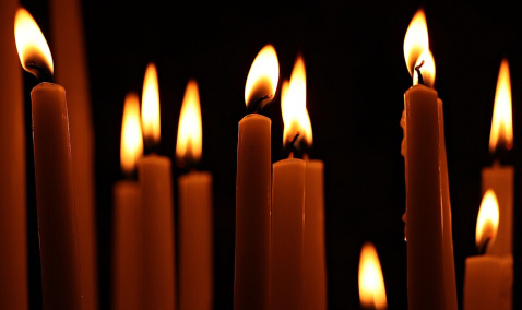 A collection of lit candles in darkness