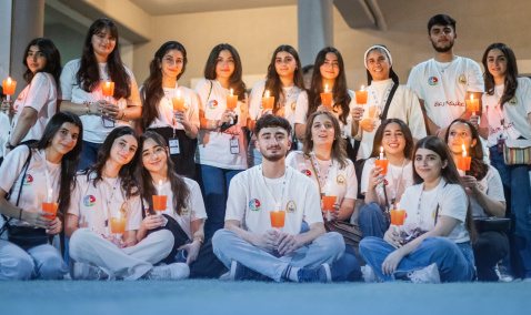 University students in Iraq sitting and standing together holding candles