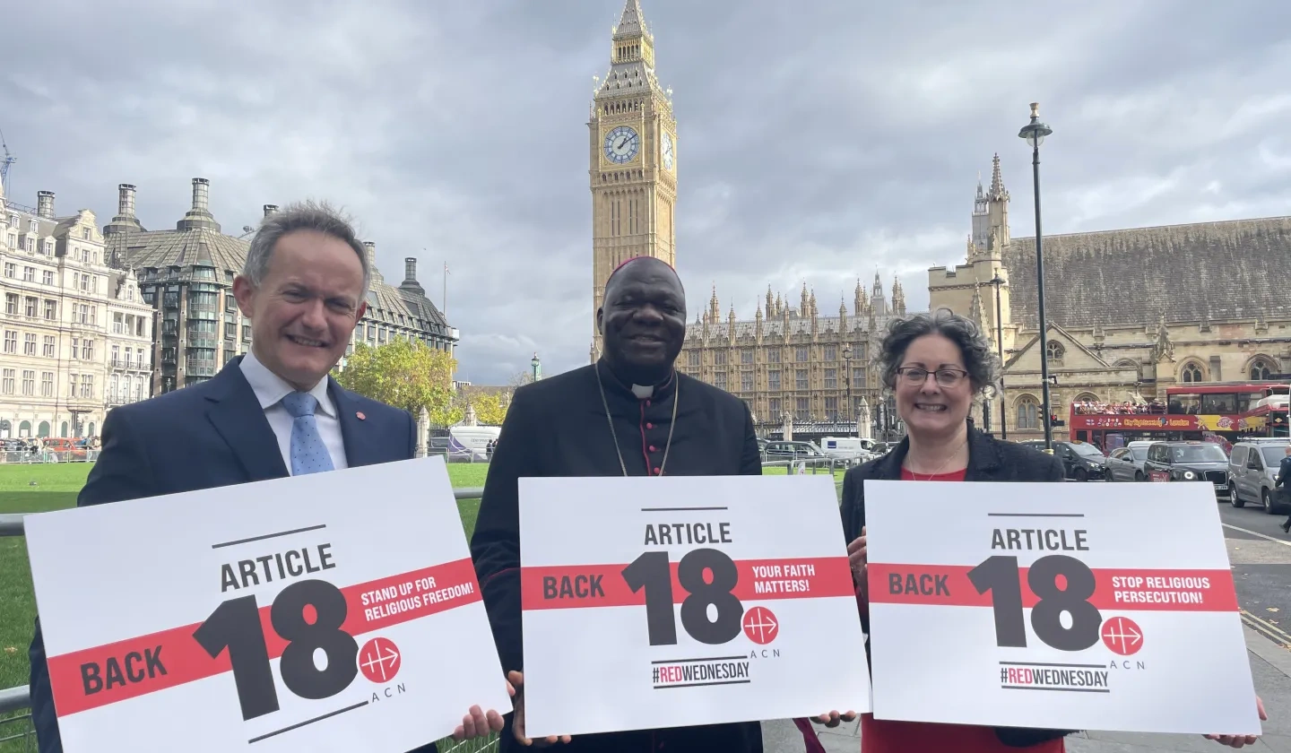 John Pontifex, Bishop John Bakeni and Dr Caroline Hull in front of Parliament holding up signs that read back article 18 
