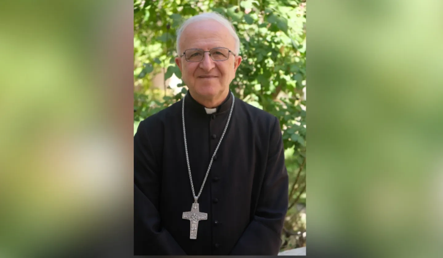 Bishop Shomali in front of a green tree