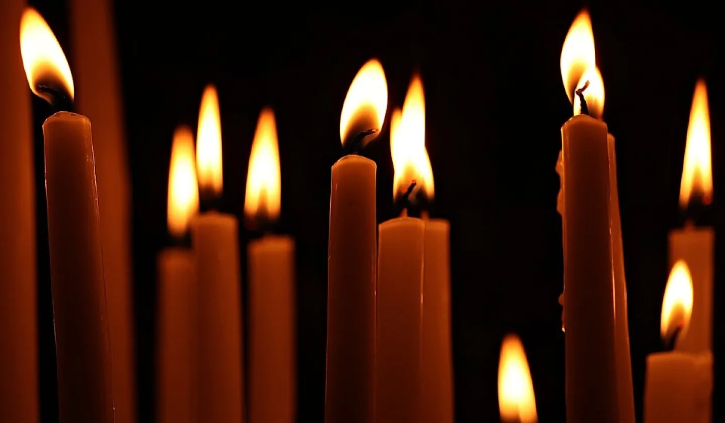 A collection of lit candles in darkness