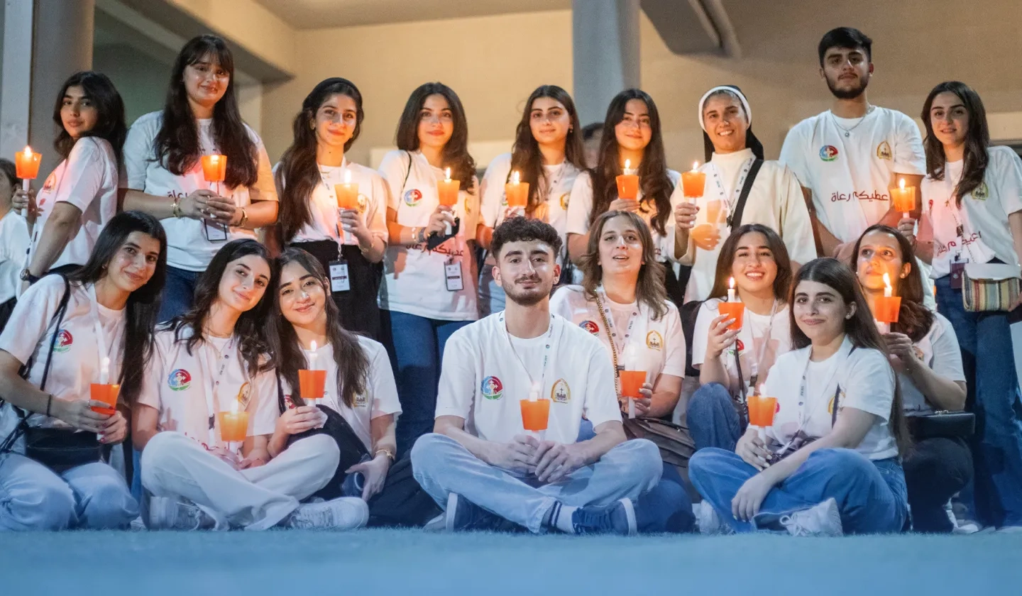 University students in Iraq sitting and standing together holding candles