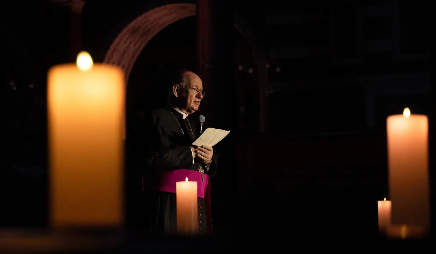 an Archbishop standing in a candle lit room