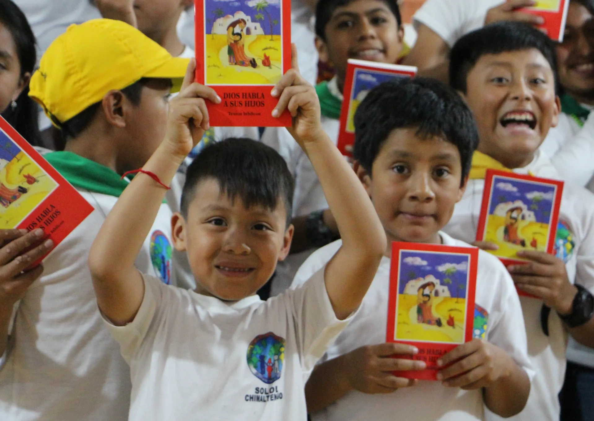 A group of children holding up the ACN child bible