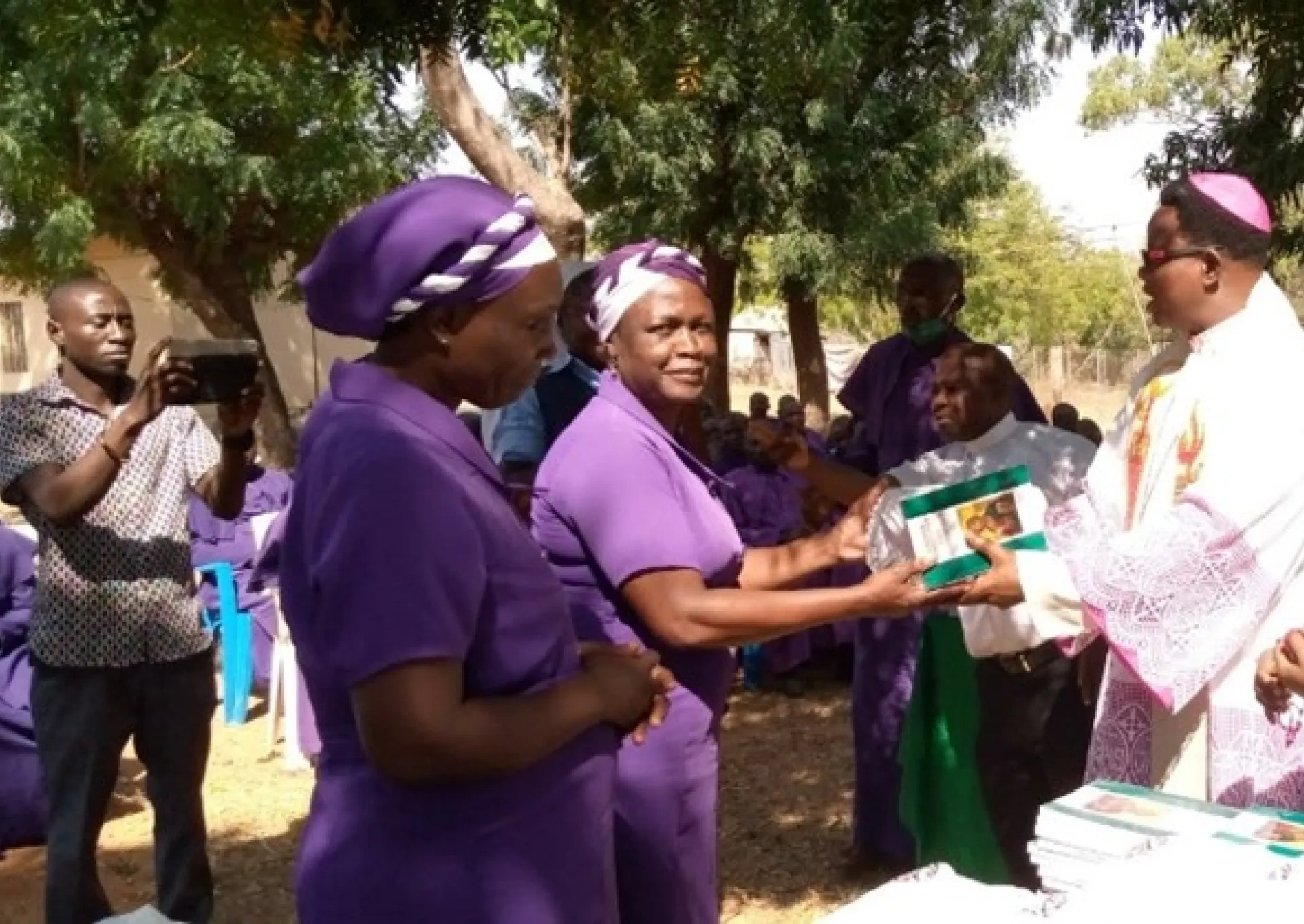 Catechists being gifted a bible from priest and Sister