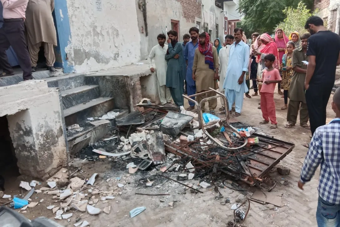 A crowd observes debris in a narrow street.
