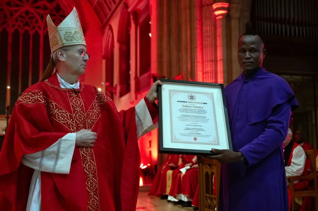 Tobias being presented with an award by bishop Nicholas Hudson