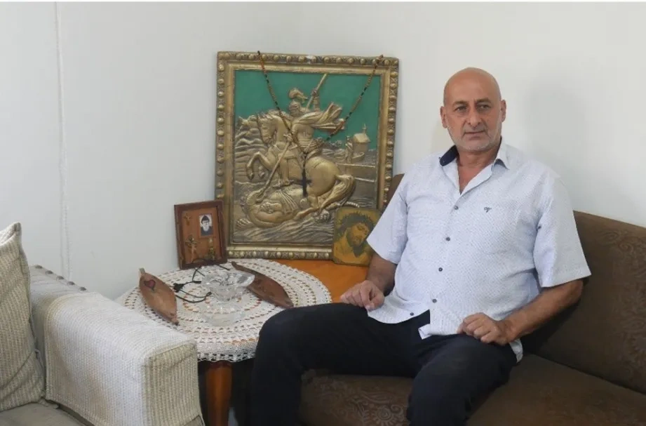 ACN emergency aid recipient sitting in his home with his picture that avoided destruction
