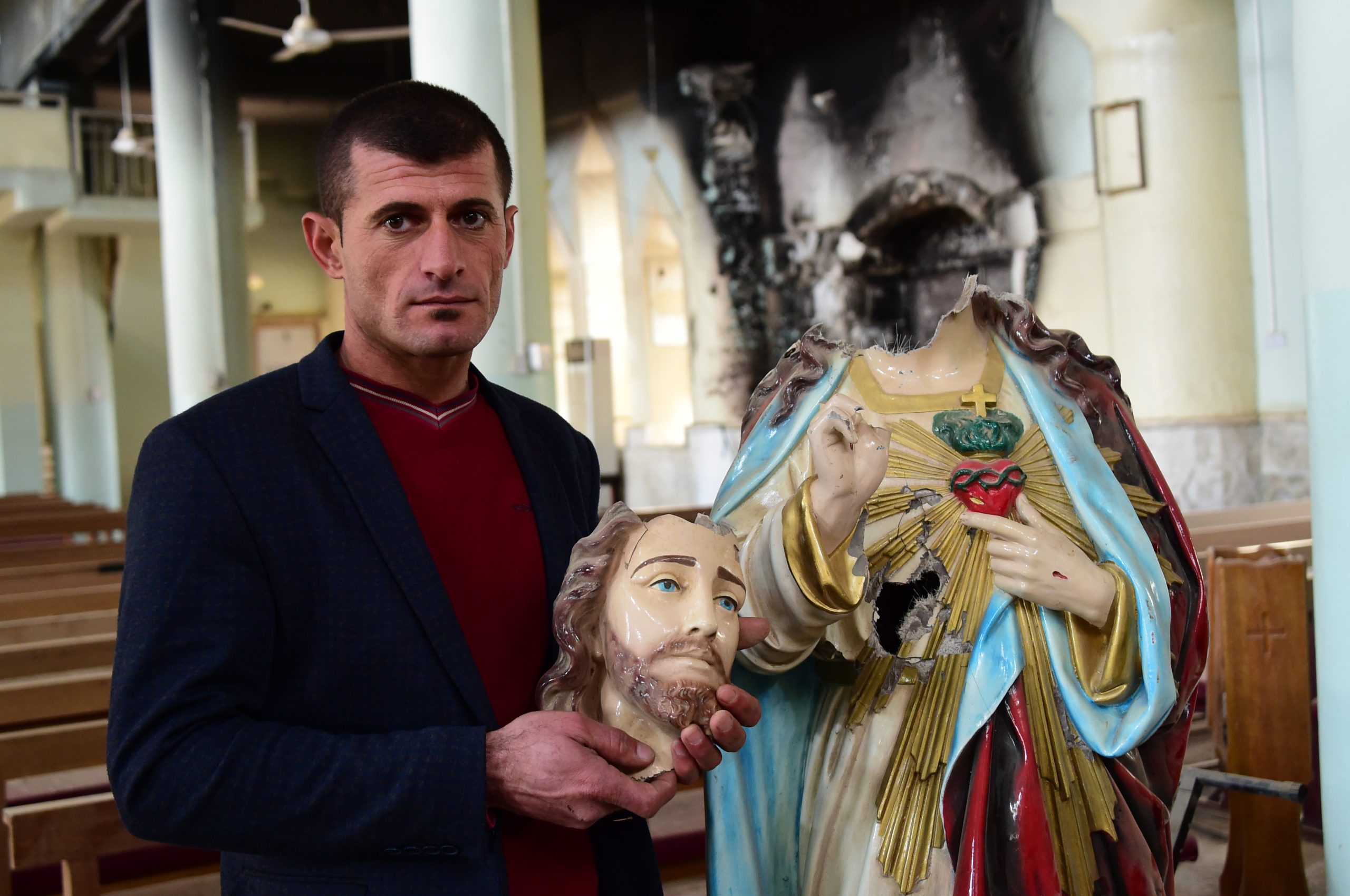 Christian holding the beheaded statue of the Sacred Heart - by Daesh (ISIS) - in St Addai Church, Iraq