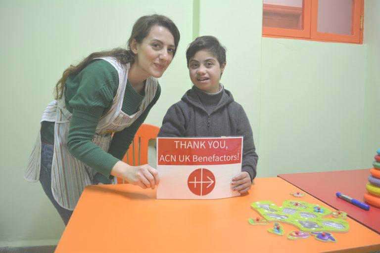Supported by her teacher, a youngster at the Mustard Seed centre in Homs shows her appreciation