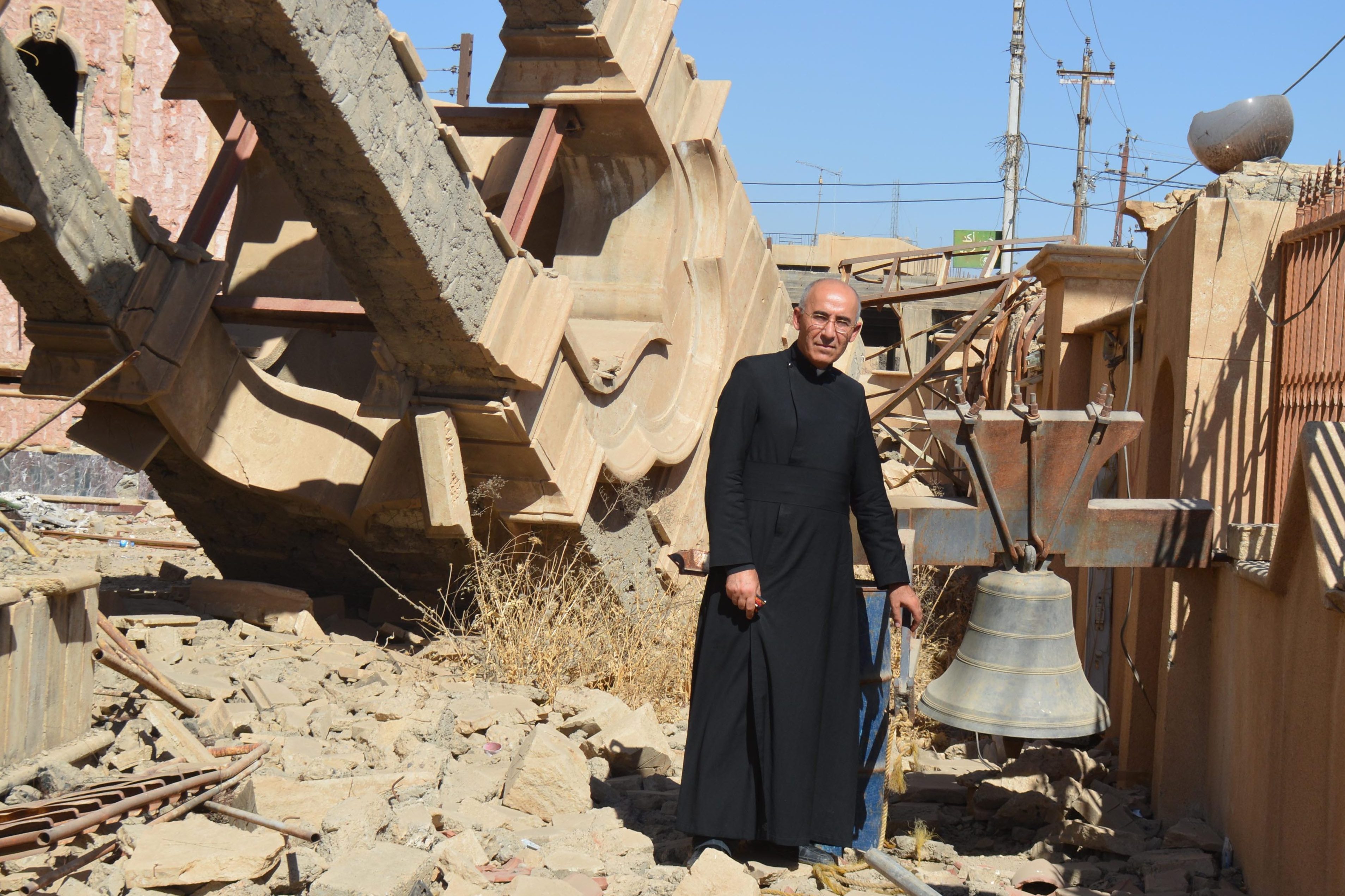 Father Georges Jahola in front of St Behnam Church’s bell tower destroyed by Daesh (ISIS) (©Aid to the Church in Need)