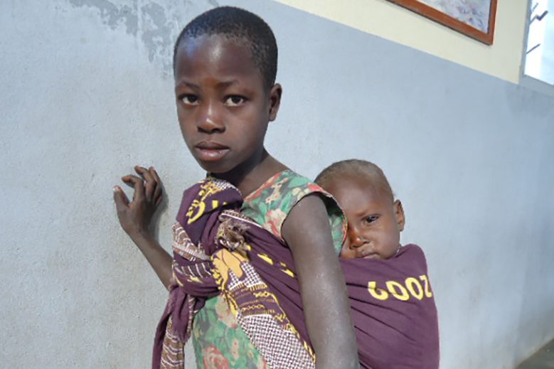 Young girl carrying a child in a cloth on her back in Tete Diocese, Mozambique (© ACN)