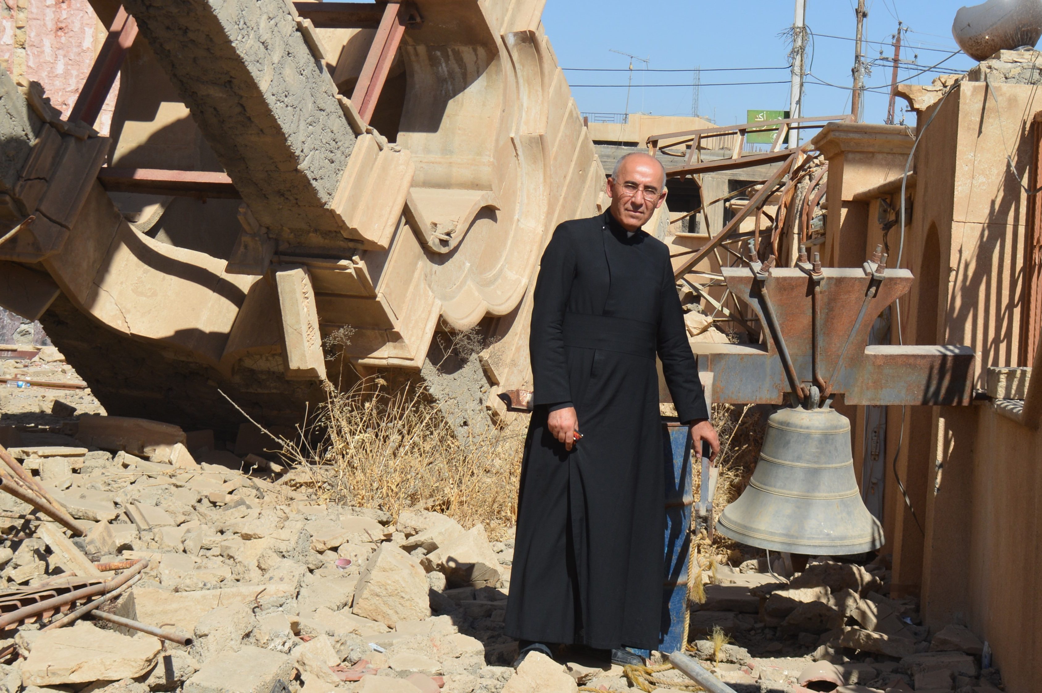 Syriac Catholic priest Father George Jahola next to the remains of the belltower of the Syriac Catholic Mar Benham Church in Baghdeda (Qaraqosh)