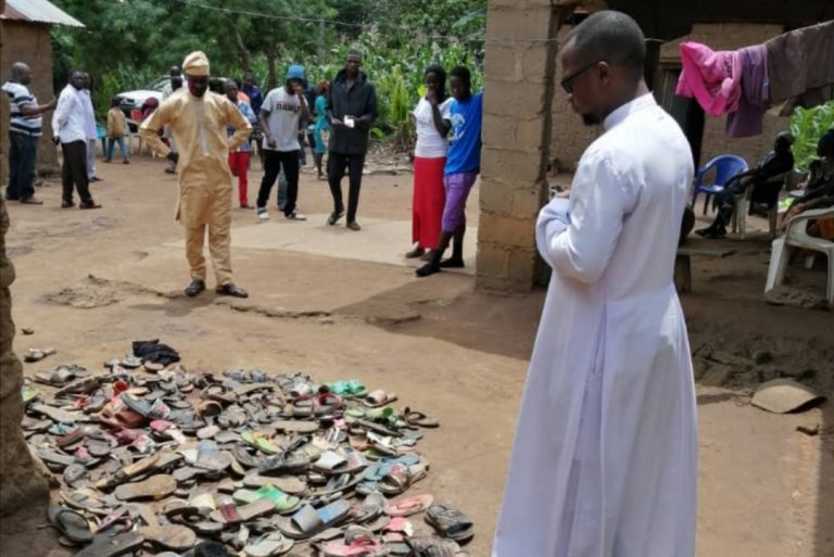 Fr. Sam Ebute in front of the dead's footwear (©Aid to the Church in Need)