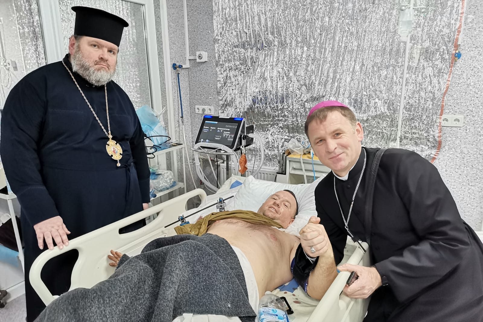 With image of Latin-rite Bishop Pavlo Honcharuk of Kharkiv-Zaporiyia (right) and Bishop Mytrofan from Kharkiv-Bohodukhovsk (Orthodox Church of Ukraine) (left) visiting an injured man (© ACN)