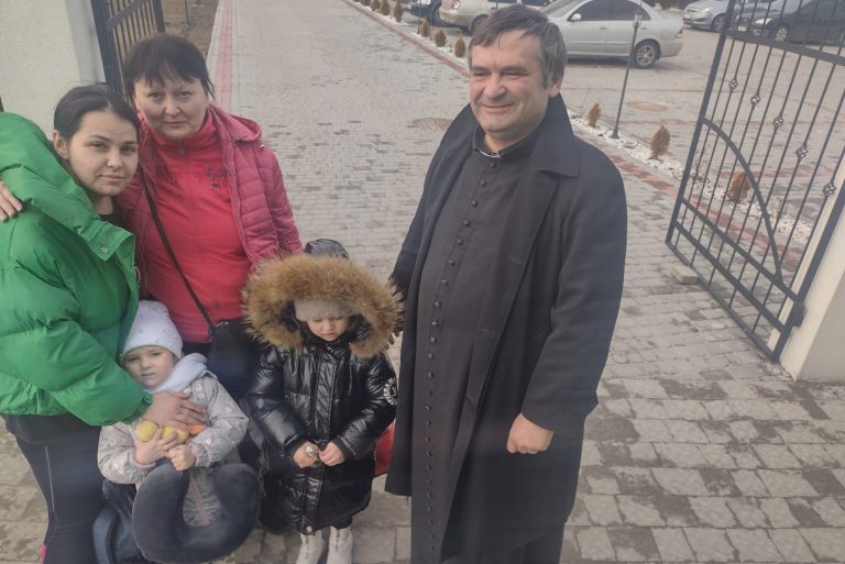 With picture of Father Grzegorz Draus with an IDP family at his parish in Lviv (© ACN).