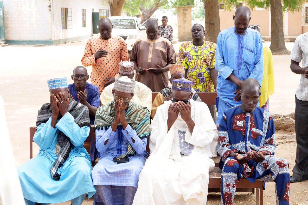 Nigerian community leaders praying together.