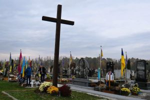 A large cross and Ukrainian flags cover a cemetery in Ivano-Frankivsk Oblast, western Ukraine.