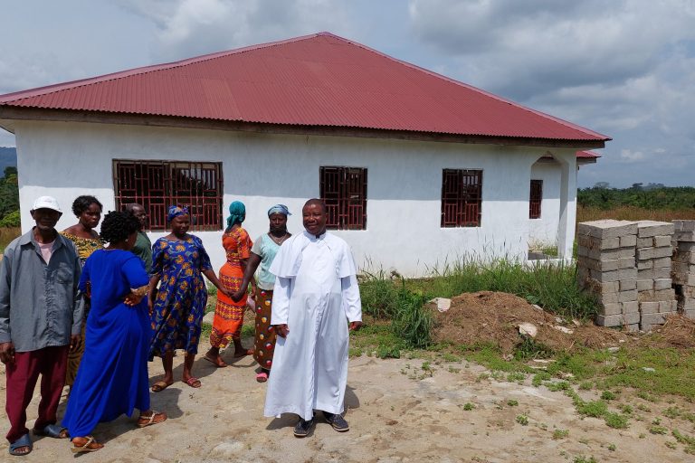 Father Augustine Amadu and parish members in front of the Immaculate Conception parish's presbytery.